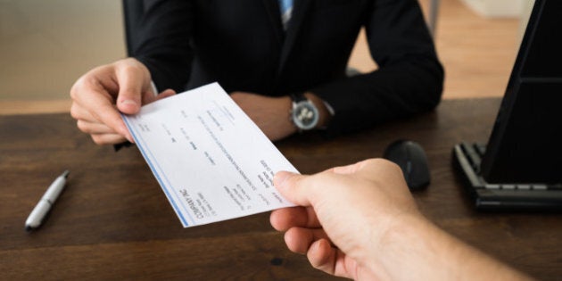 Close-up Of Businessman Hands Giving Cheque To Other Person In Office