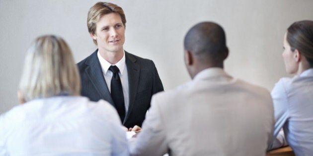 'Smart, male applicant being interviewed by a panel of business people'