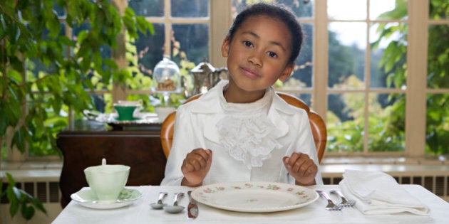 Girl (5-7) sitting at table setting, smiling