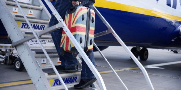 A man with a union jack suitcase boards a flight at airport.