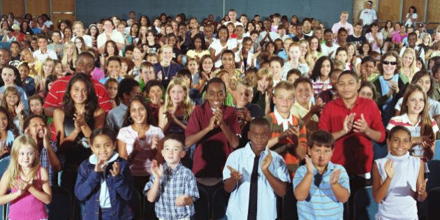 Children (6-13) in school auditorium giving standing ovation, portrait