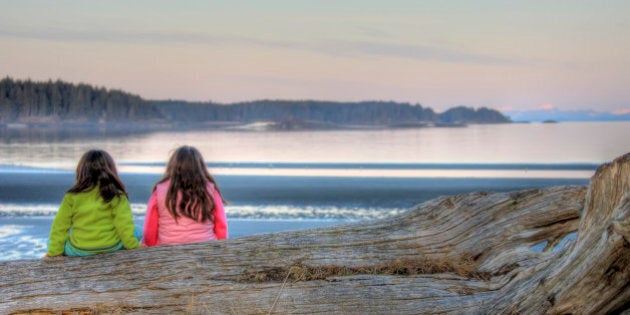 Young First Nation girls sitting on a log, Vancouver Island, British Columbia