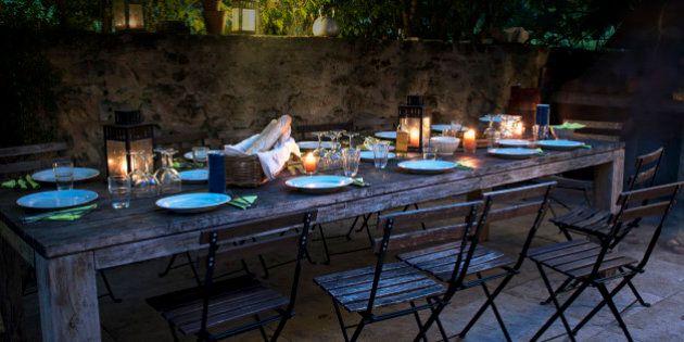 large rustic table on the terrace prepared for a outside dinner with friends from the evening until late at night