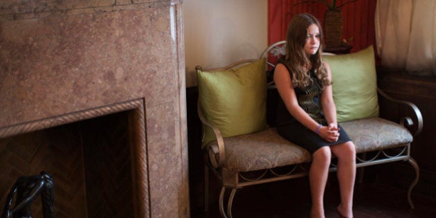 Portrait of unhappy girl sitting on seat in living room