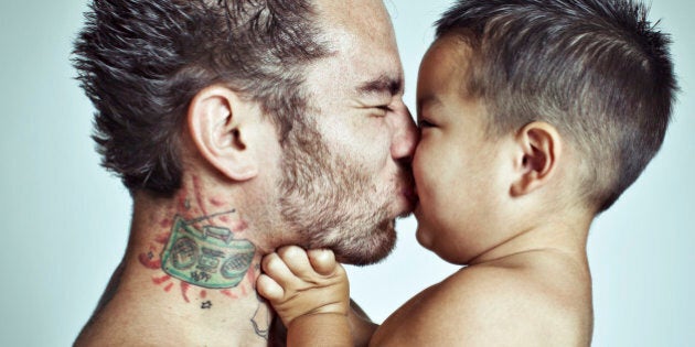 Playful baby boy gets close and makes a scrunchy face to kiss his dad.