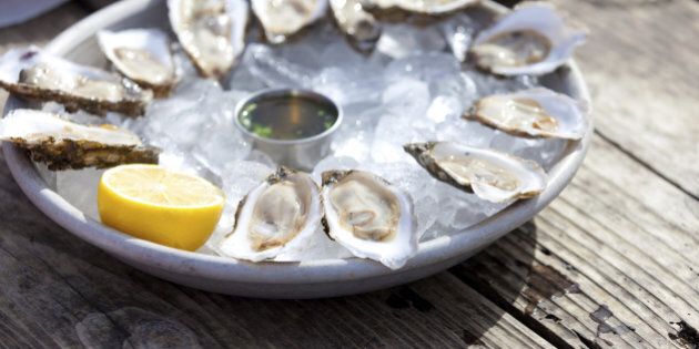 fresh raw oysters served with lemon and sauce at the plate with ice
