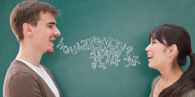 Portrait of smiling male teacher and student in front of chalkboard holding hands