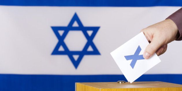 Hand inserting a ballot to ballot box. Flag of Israel in the background.