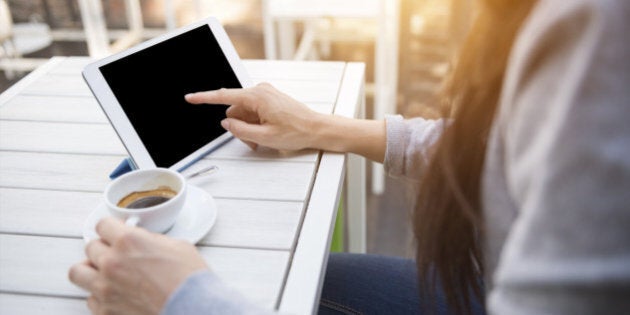 Close up shoot of a young caucasian businesswoman at the cafè during the breakfast using her digital tablet with blank screen and drinking an italian 'espresso' coffee.