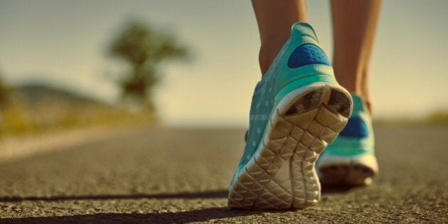 Closeup of athlete female feet in running shoes jogging on the road early in the morning. Healthy lifestyle.