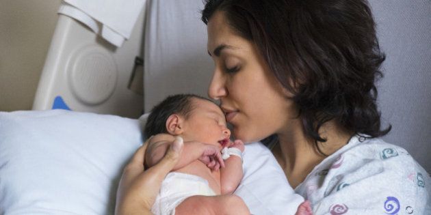 Mother kissing newborn baby in hospital