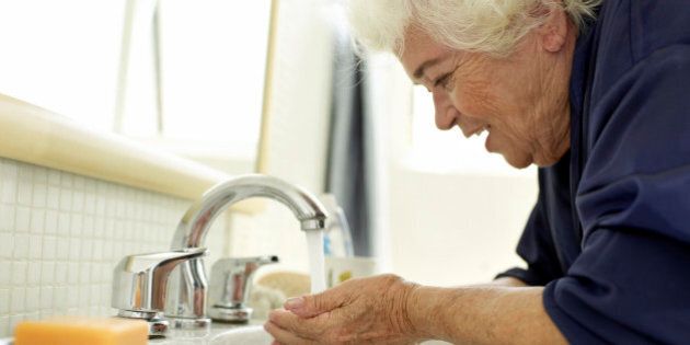 Elderly woman washing her face after wake up