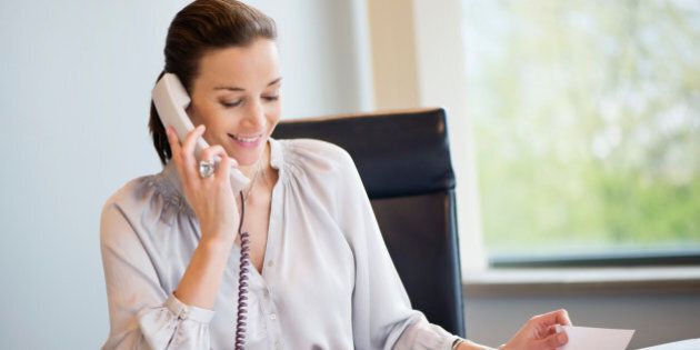 Businesswoman talking on a landline phone in an office