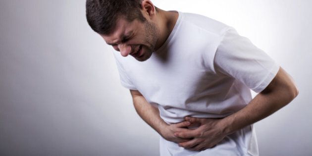 Young man with severe stomachache holding his stomach