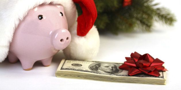 Part of piggy bank with Santa Claus hat and stack of money american hundred dollar bills with red bow and christmas tree standing on white background