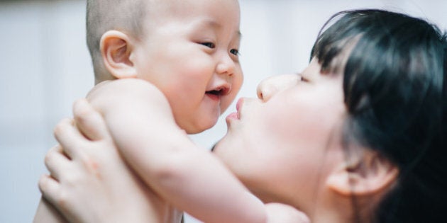 Mother holds and kisses her baby