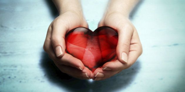 two hands holding red crystal heart