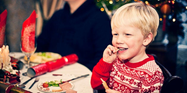 Happy smiling little boy enjoying his Christmas dinner with family.