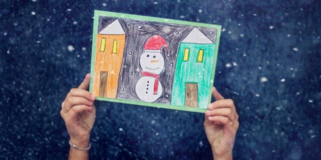 child hands holding a hand made christmas card with snowman and winter houses,Blue , snow background