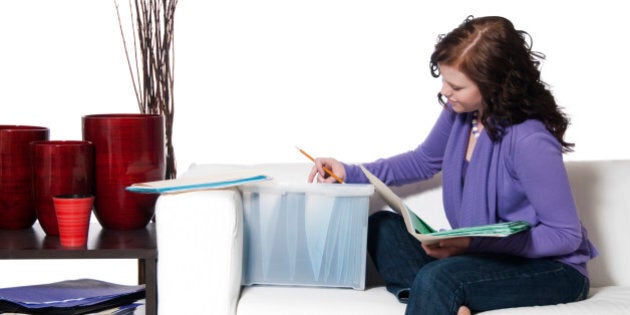 Young woman in living room setting filing and doing paperwork.