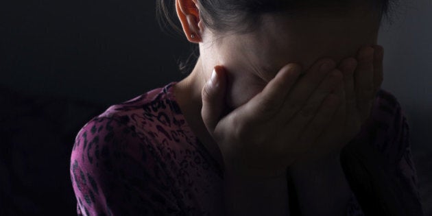 girl crying in the darkness covering her face