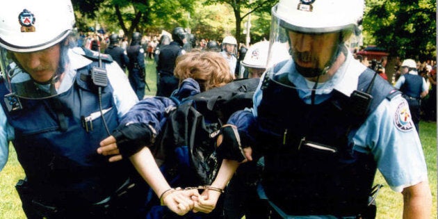 TORONTO, ON - JUNE 15: Anti-poverty protesters threw molotov cocktails, paint bombs and fist-sized chunks of concrete at police in front of the Ontario Legislature yesterday to protest the government's social policies. Hundreds of protesters battled scores of Toronto police in an hour-long skirmish - the worst violence the Legislature has seen - to protest homelessness, the abolition of rent controls and other social policy measures. The trouble began after John Clarke, organizer for the Ontario Coalition Against Poverty (OCAP) which led the march, was denied access to the Legislature to address MPP's. Met with locked doors and lines of police in riot gear Clarke encourage demonstrators to don gas masks and eye shields. June 15, 2000. (Boris Spremo/Toronto Star via Getty Images)