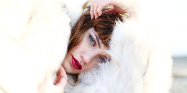 A model in a white fur coat poses during a photo shoot on a rooftop.