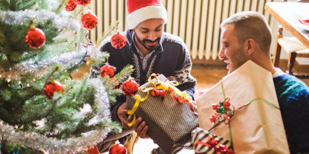 Gay interracial couple exchanging gifts under the christmas tree