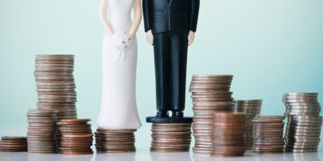 Close up of wedding cake figurines on stacks of coins
