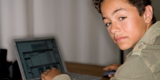 portrait of latino teenage boy sitting with his laptop