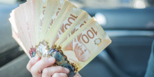 A woman counts $100 Canadian notes/bills before making a large purchase.