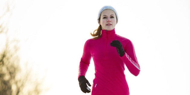 Winter running - Young woman running cross-country outdoors on a cold winter day (motion blurred image, color toned image)