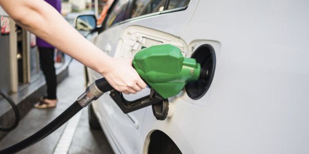 Female hand holding green pump filling gasoline