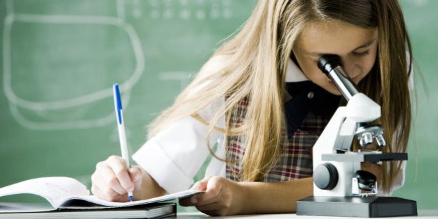 girl working in a classroom with a microscope