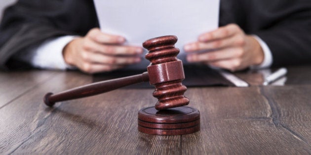 Close-up Of Male Judge In Front Of Mallet Holding Documents