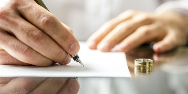 Closeup of a man signing divorce papers.