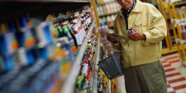 Mature man shopping for groceries, reading label of can