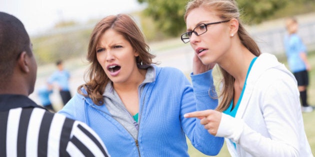 Angry soccer moms yelling at referee during kids' game.