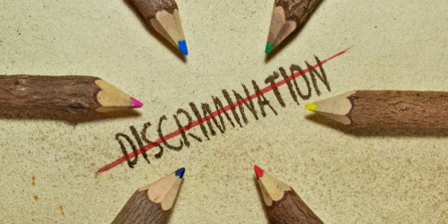 Conceptual image with pencils on vintage background to stop discrimination. Six handcrafted wooden pencils arranged in a circle and the word Discrimination with red line in the middle.