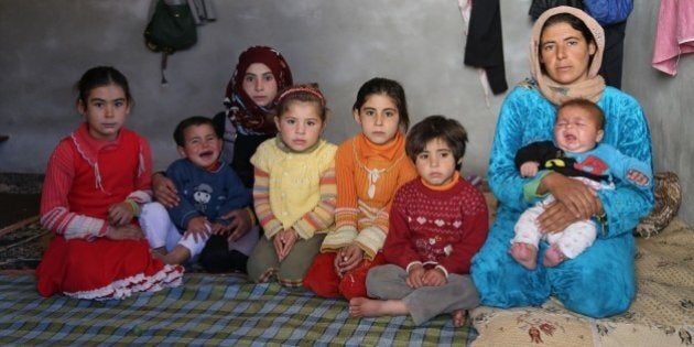 HATAY, TURKEY - NOVEMBER 22: A Syrian refugee woman, fled from her home due to civil war is seen with her children at a house in Reyhanli district of Hatay on November 22, 2015. Syrian refugee families who fled their country due to the ongoing civil war try to hold on to life as they live in rented houses, tents and storehouses. (Photo by Cem Genco/Anadolu Agency/Getty Images)