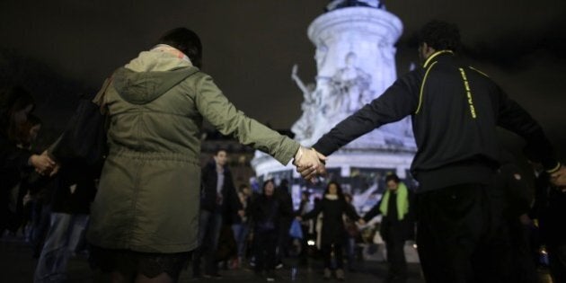 People hold hands near a makeshift memorial for the victims of a series of deadly attacks in Paris, at the Place de la Republique in Paris on November 20, 2015. Gunmen and suicide bombers went on a killing spree in Paris on November 13, attacking the concert hall Bataclan as well as bars, restaurants and the Stade de France. Islamic State jihadists operating out of Iraq and Syria released a statement claiming responsibility for the coordinated attacks that killed 130 and injured over 350. AFP PHOTO / KENZO TRIBOUILLARD (Photo credit should read KENZO TRIBOUILLARD/AFP/Getty Images)