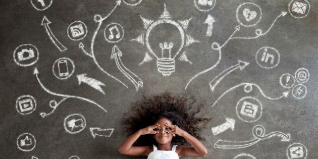 African girl in white dress, explores a chalkboard of tech symbols, visualizes the future