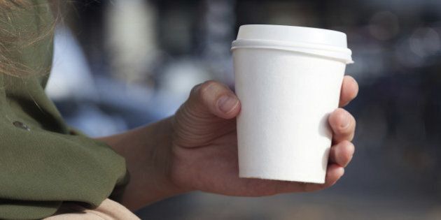 Young woman drinking coffee from disposable cup