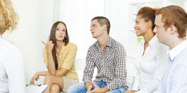 'Group Therapy, meeting of support group with their counselor. Selective focus to young woman talking.'