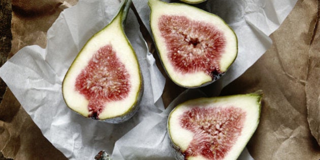 Cut figs on brown paper on a wooden kitchen surface