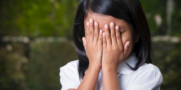 Shy 8 year old Filipino girl covering her face in Cebu City, Philippines.