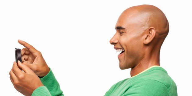 Side view of happy African American man taking self portrait with cell phone. Horizontal shot. Isolated on white.