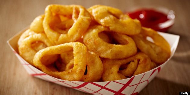 Fried onion rings on a paper tray, shot with very shallow focus with ketchup soft in the background. Professionally color corrected, exported 16 bit depth, retouched and saved for maximum image quality.