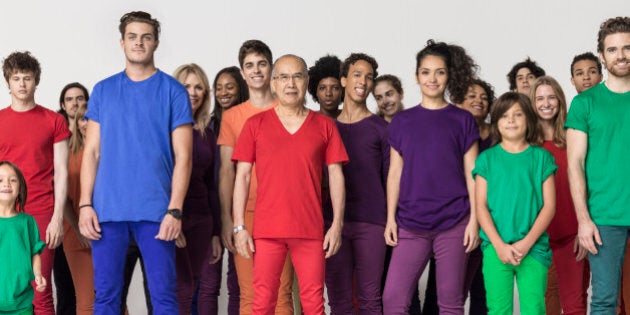 Studio shot of a mixed age, multiethnic large group of smiling men and women, wearing monochromatic colors