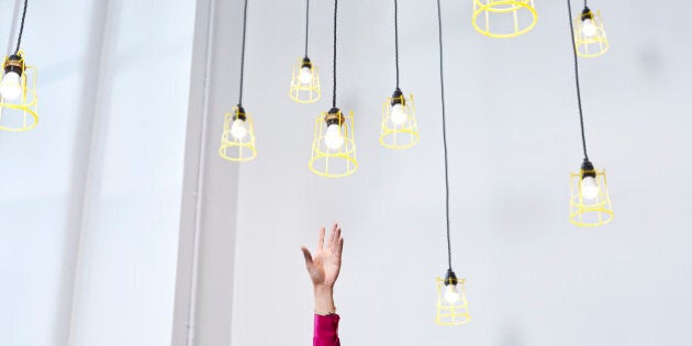 A hand reaching for conceptual idea lightbulbs